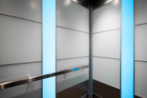 FSRT810 Интерьер лифта Levele-107 с захватными панелями из стекла vivichrome chromis с белой прослойкой и отделкой pearlex +, нержавеющей стали с отделкой seastone и узором dallas; панели для лайтплана из вивихромированного хромисового стекла с прослойкой