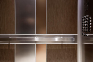 FSRT688 Интерьер лифта Levele-101 с главными панелями из склеенной бронзы с натуральной патиной и рисунком травы; большие акцентные панели из нержавеющей стали с льняной отделкой; небольшие акцентные панели из стекла vivichrome chromis с прослойкой индиви